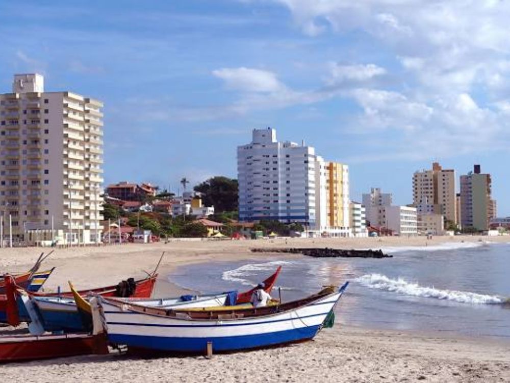 Barcos na praia e prédios residenciais em Barra Velha SC. A segurança e o índice de criminalidade em Barra Velha SC influenciam a qualidade de vida.